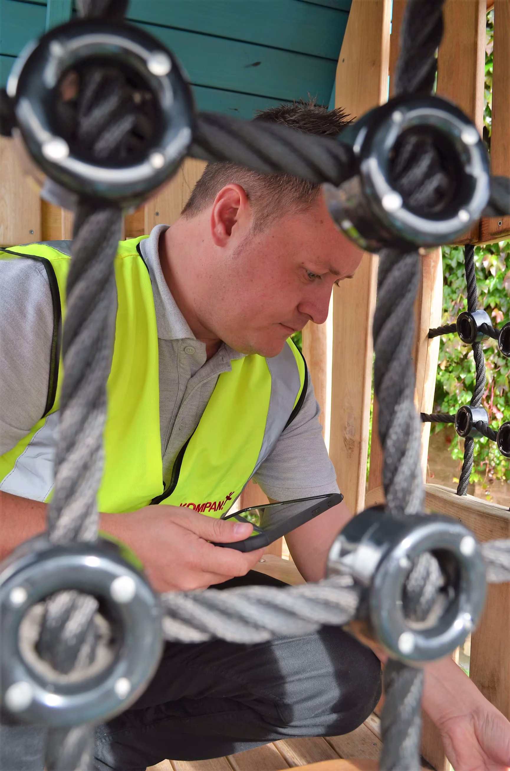 En man i gul väst underhåller en lekplats