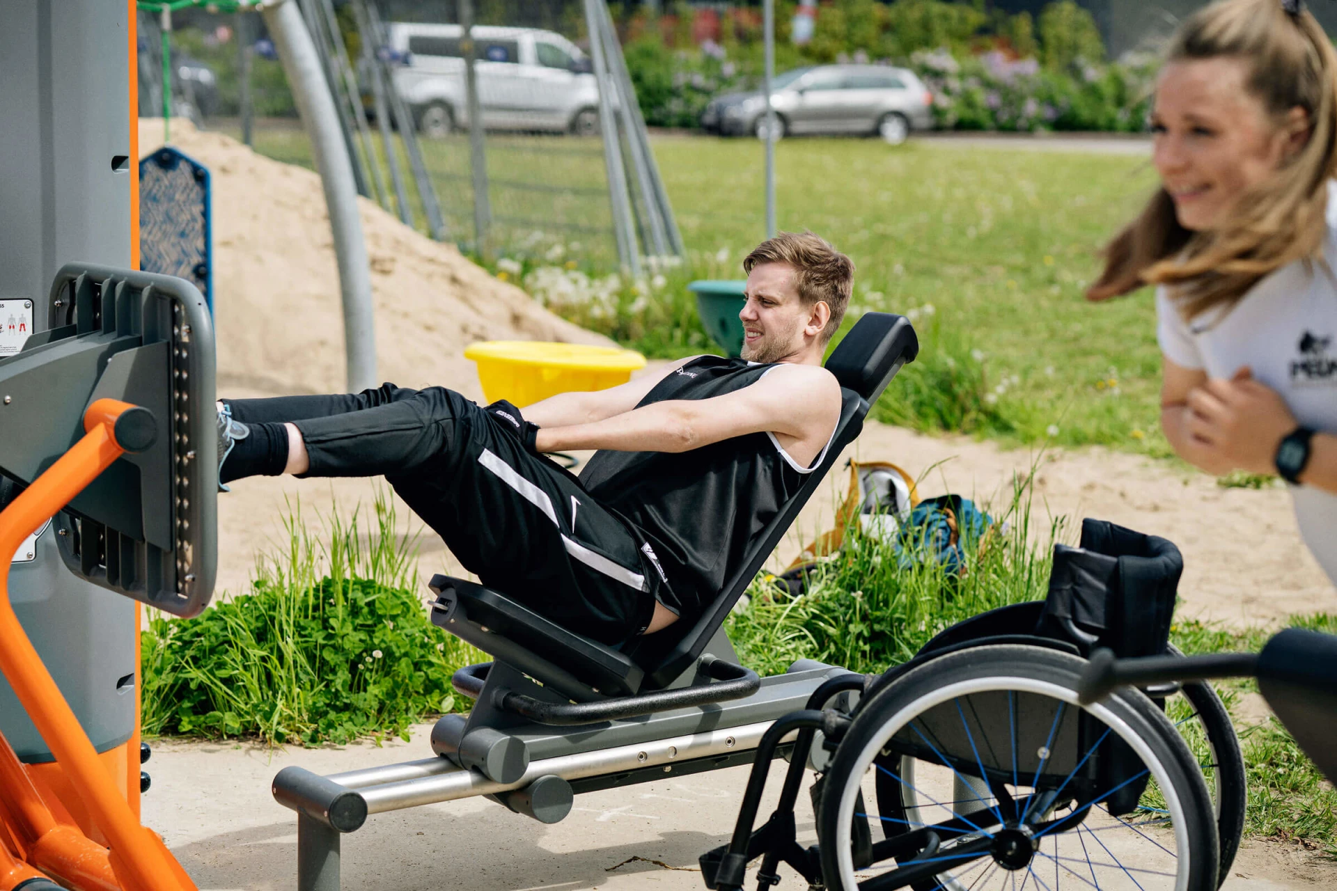 휠체어를 탄 남성이 야외에서 장애인용 운동기구로 운동하고 있습니다.