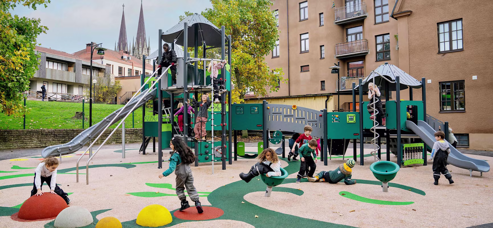 Children playing on a large playground tower made from more sustainable materials in Olins Park