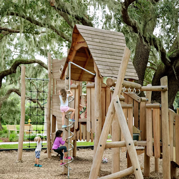 Girls playing on natural playground in forest at Tucker Ranch