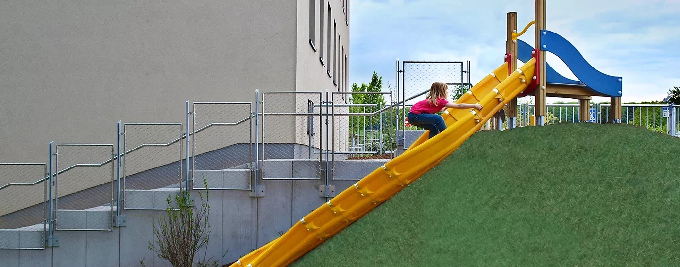 girl sliding down a playground slide from top of a hill