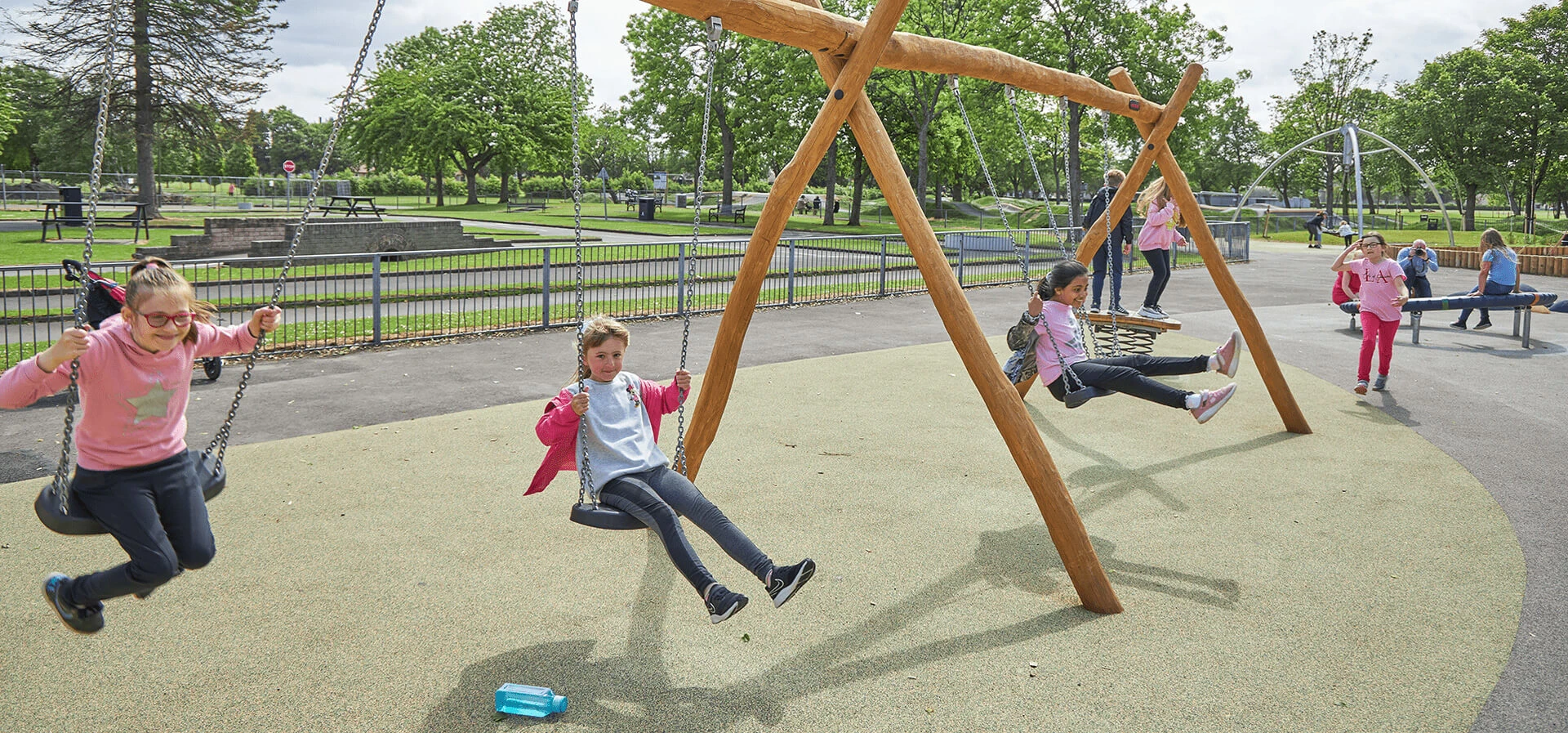 children playing on classic large wooden swings hero image