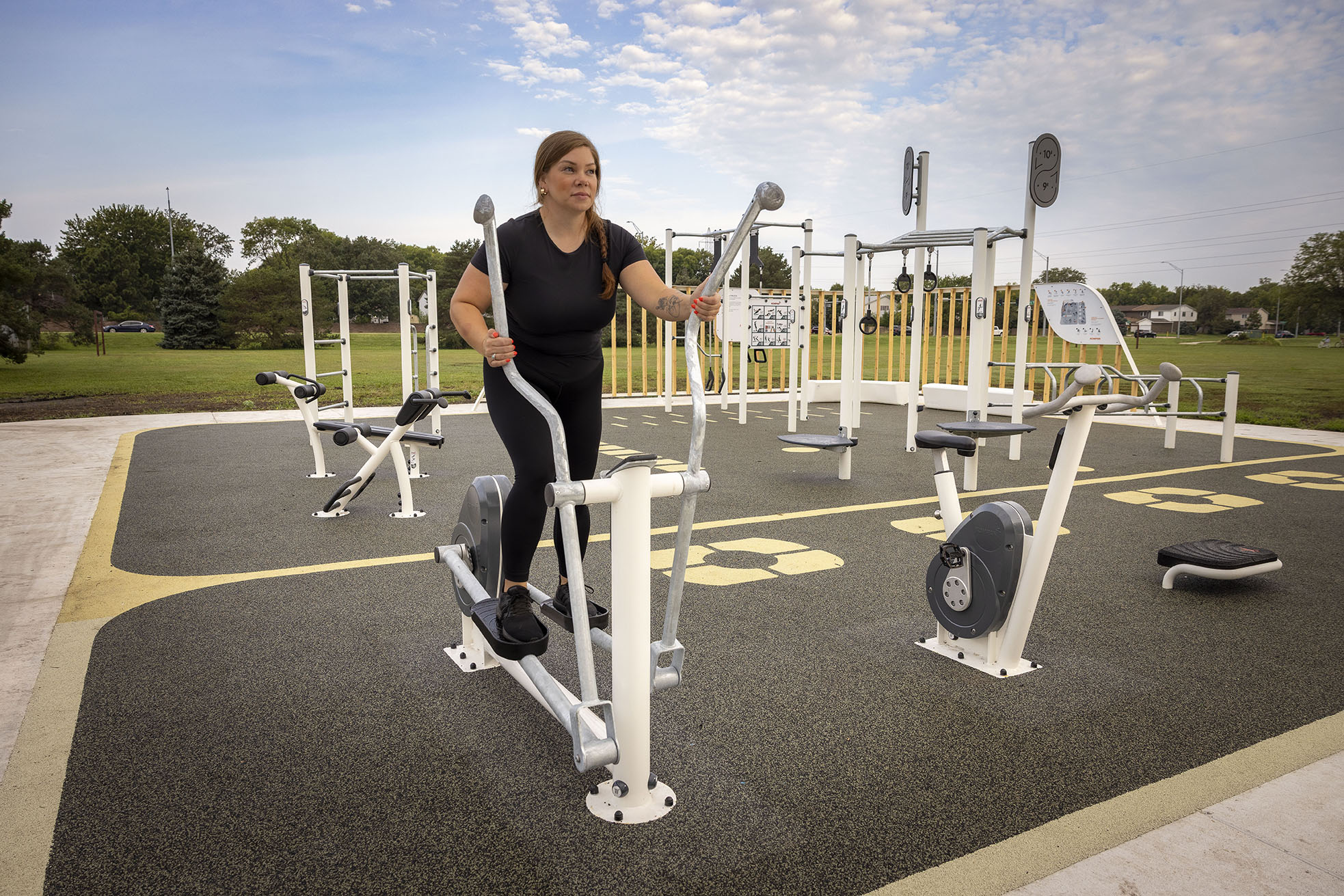 Woman exercising on cross trainer at KOMPAN FitBLOCK outdoor fitness area in Lincoln, Nebraska
