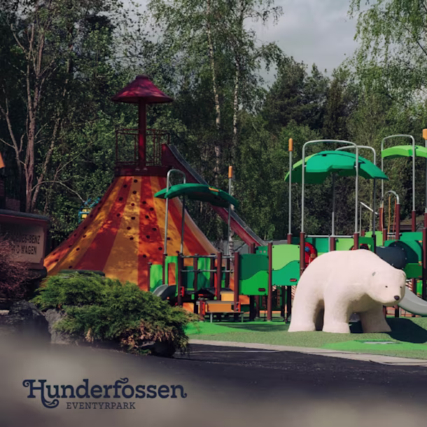 Colorful playground with slides and climbing structures, a large white polar bear sculpture, and green trees in the background.