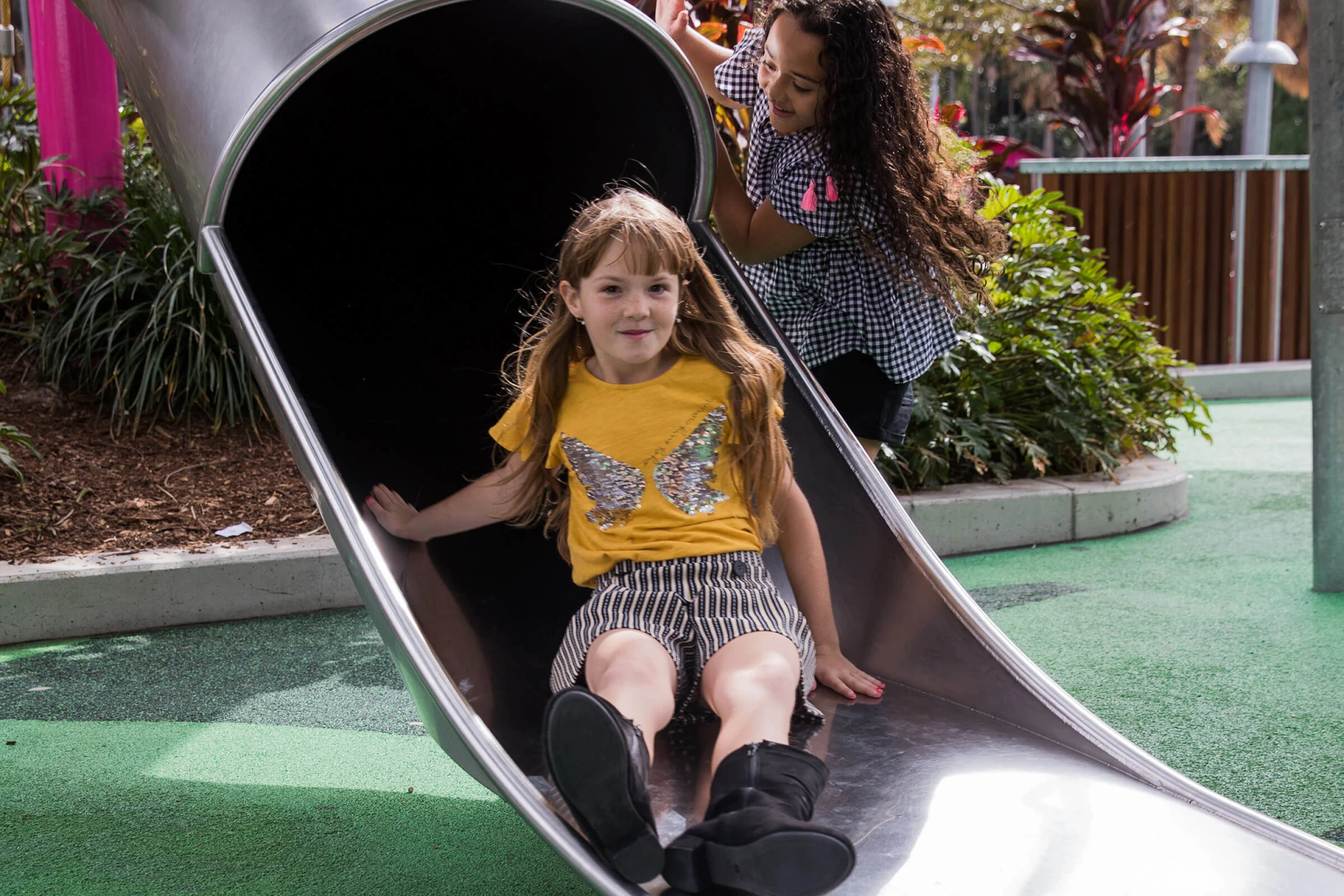 A girl on a playground sliding down an embankment tunnel slide