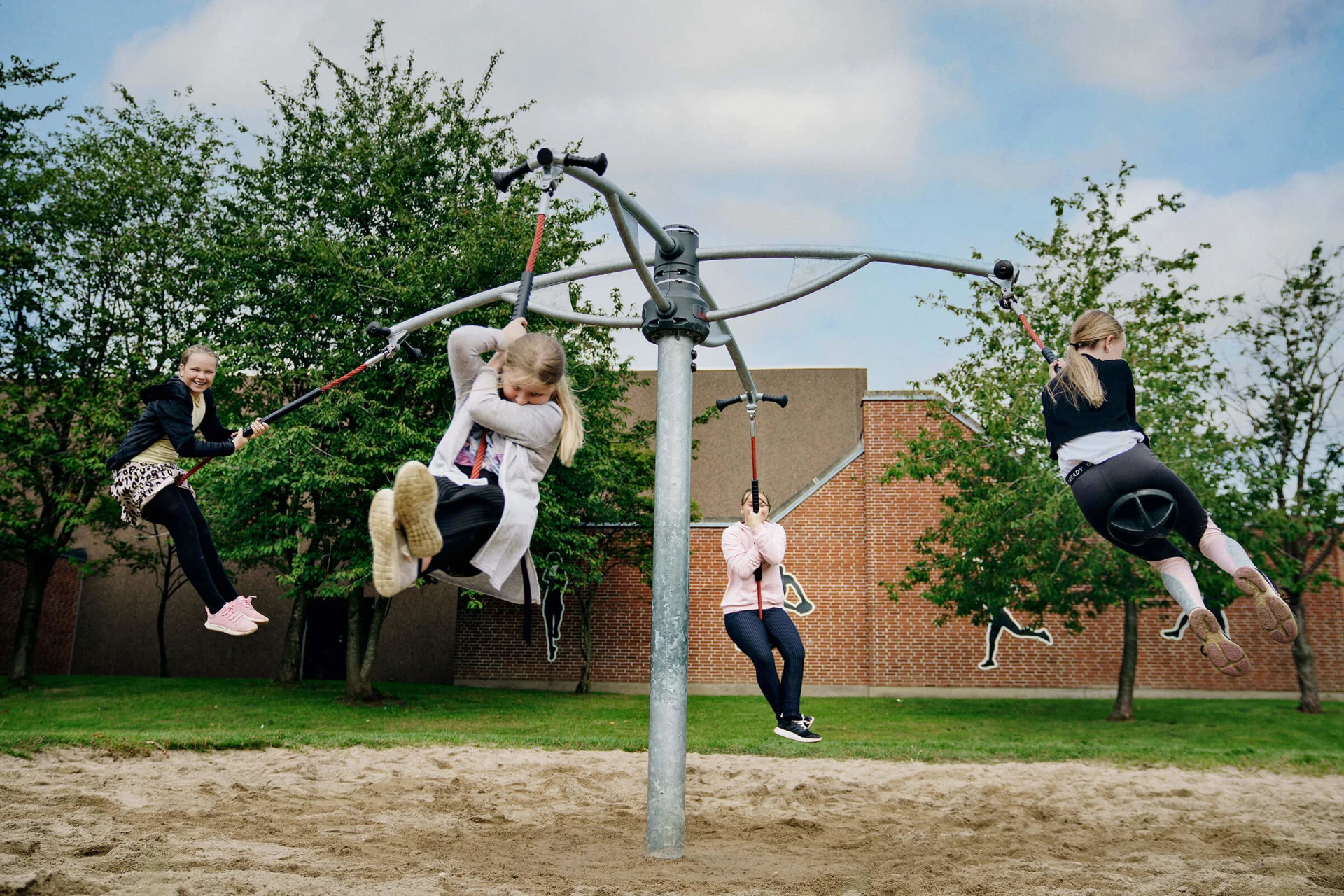 Tweens playing on a spinning swing set