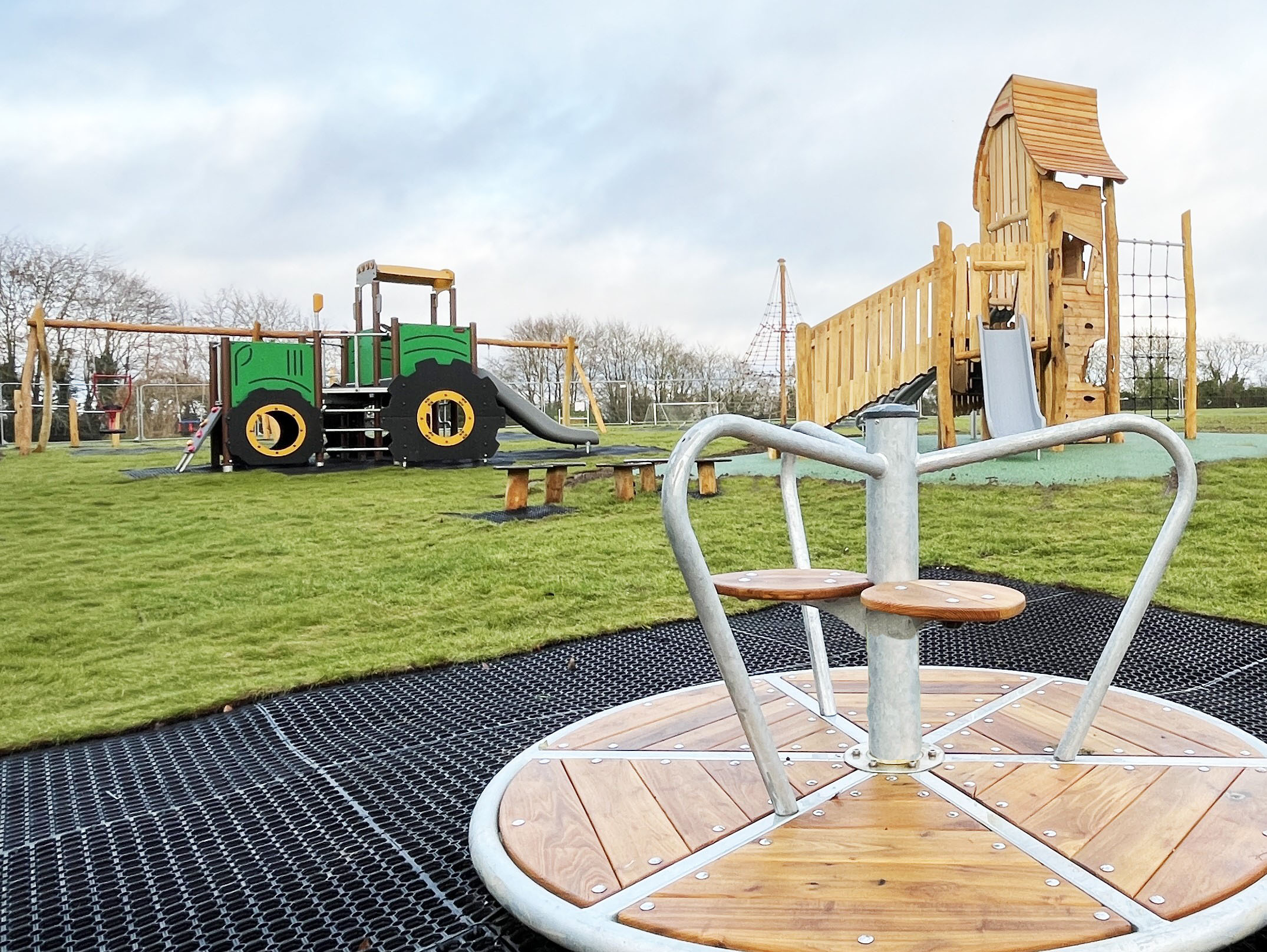 A natural wooden playground with tractor themed play system