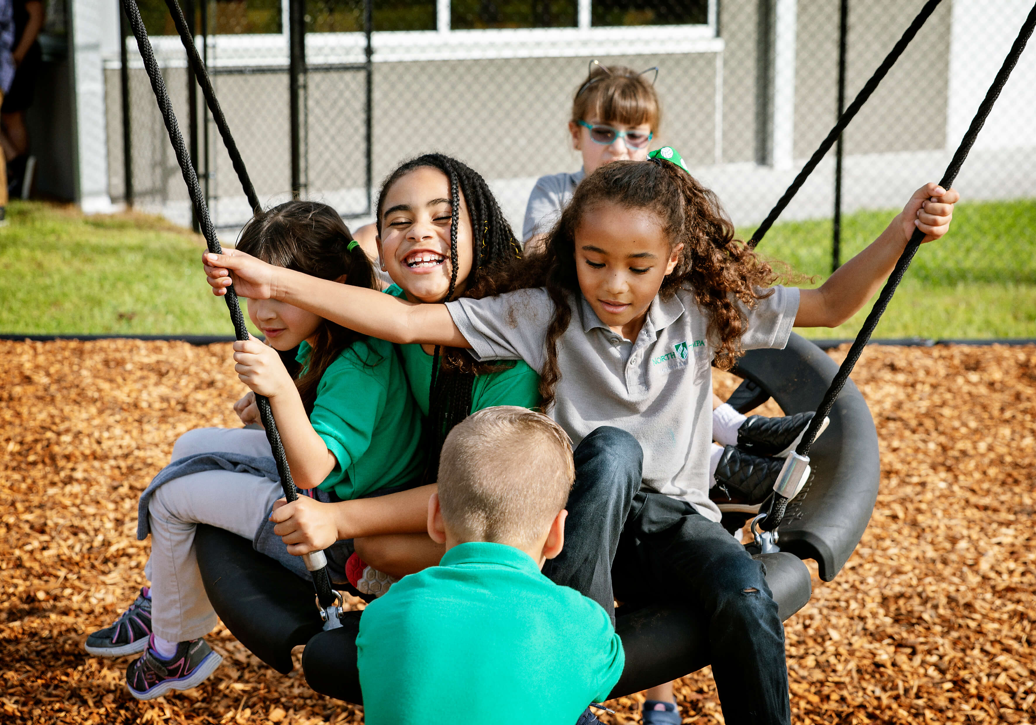 Children in school uniforms playing on a swing together