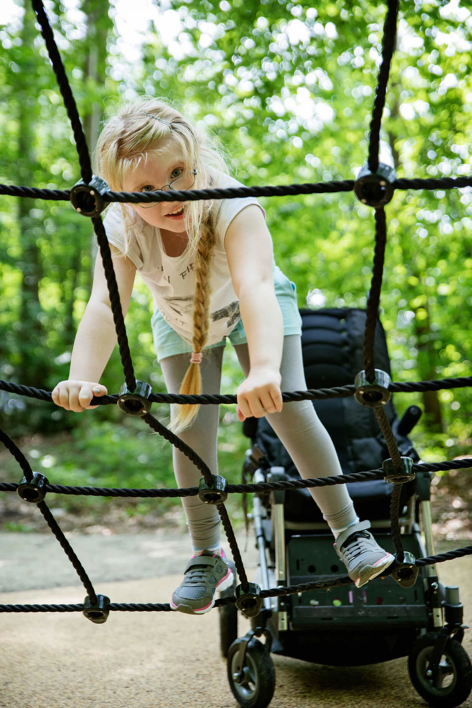 A girl climbing on a climbing net on playground 