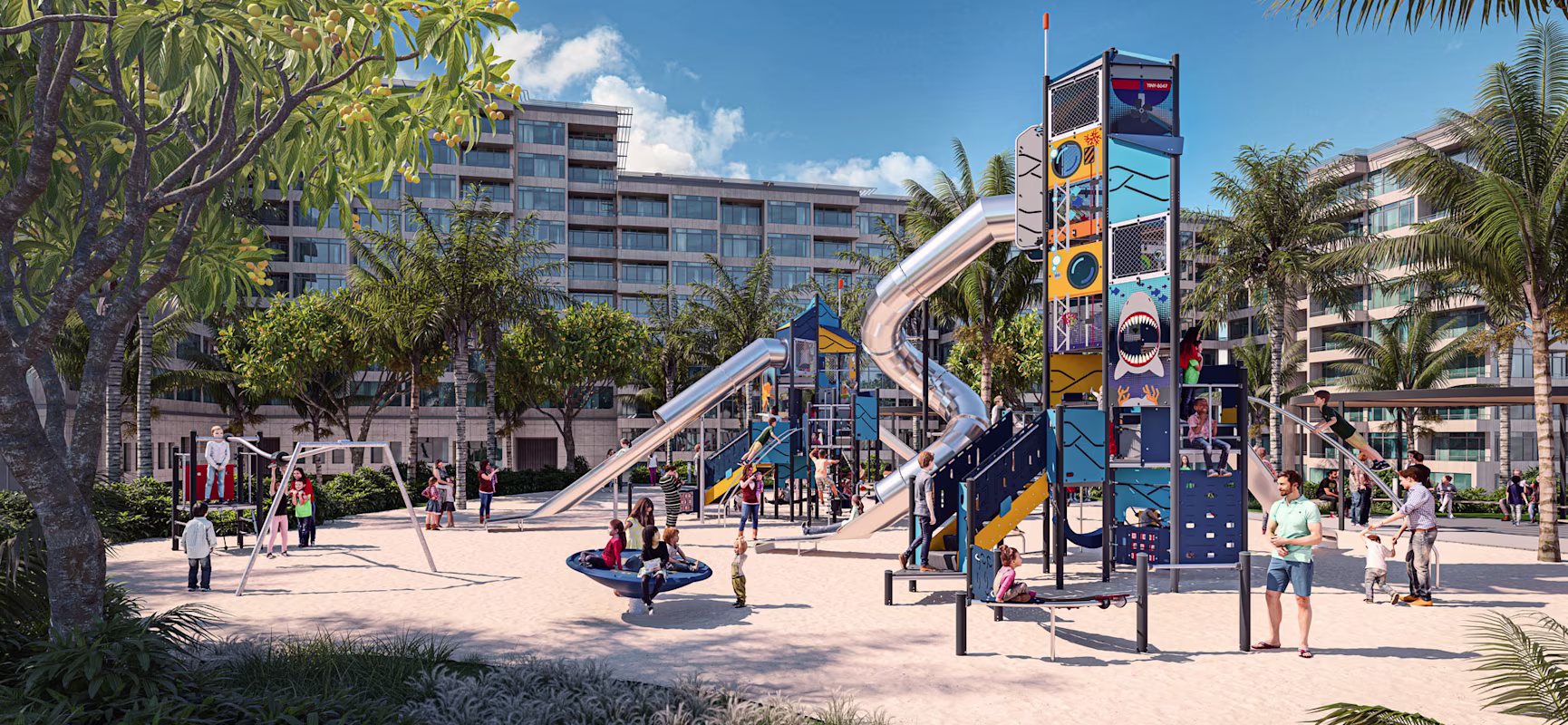 Children and adults play on colourful slides and climbing structures in a sunny sandy playground, with palm trees and apartments behind.