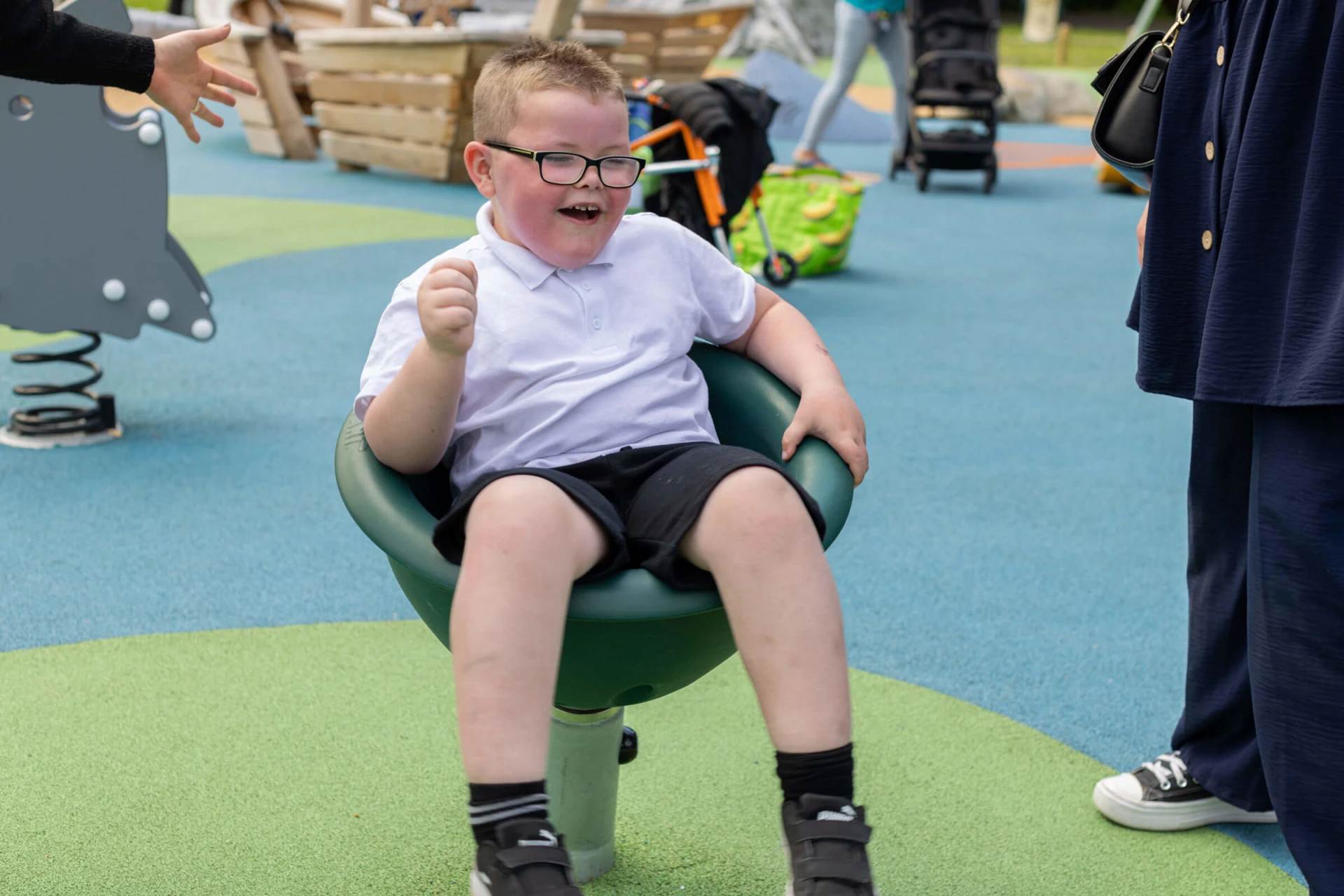 a care taker and a boy in wheelchair playing on a playground