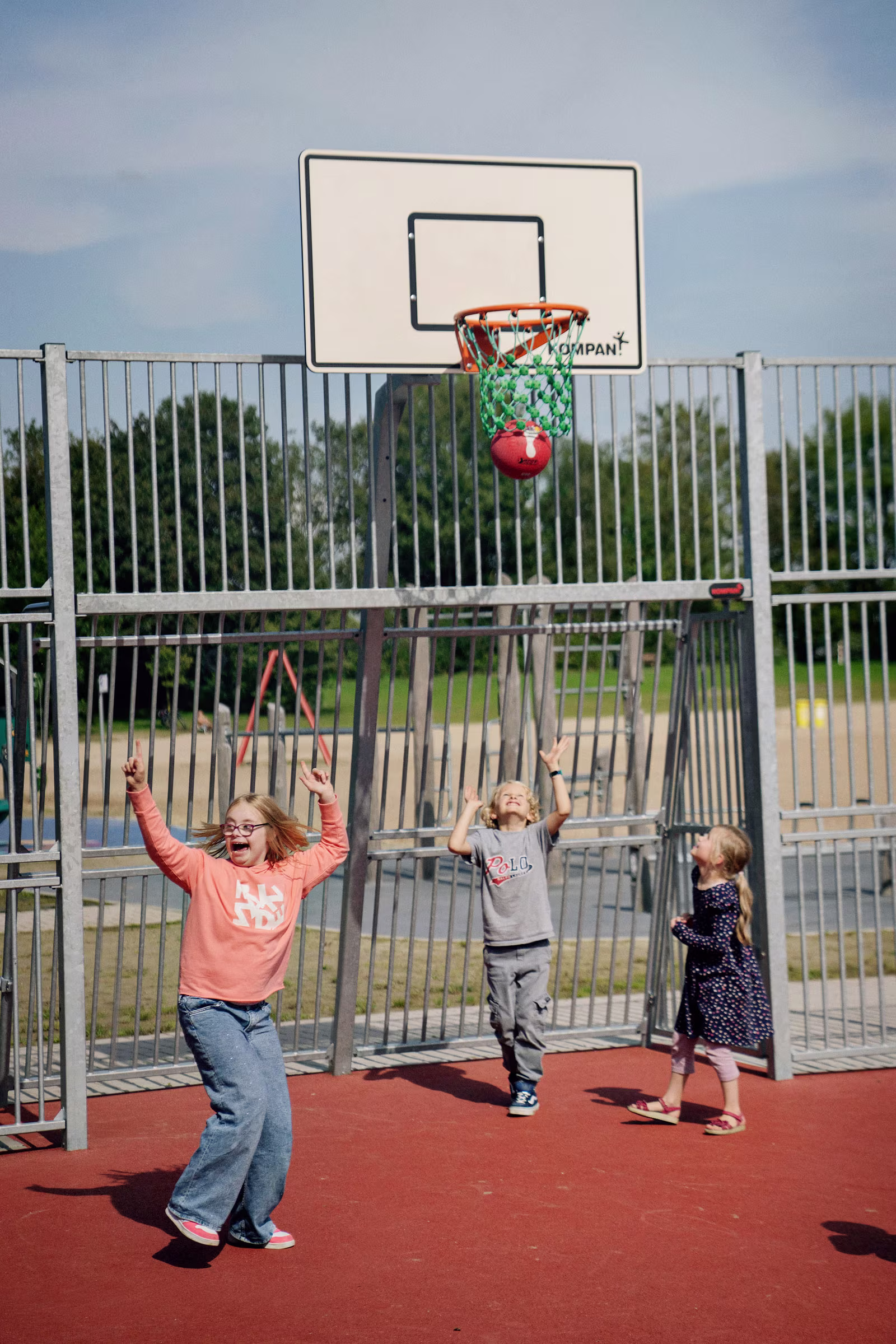 eine Betreuerin und ein Junge im Rollstuhl spielen auf einem Förderschule Spielplatz
