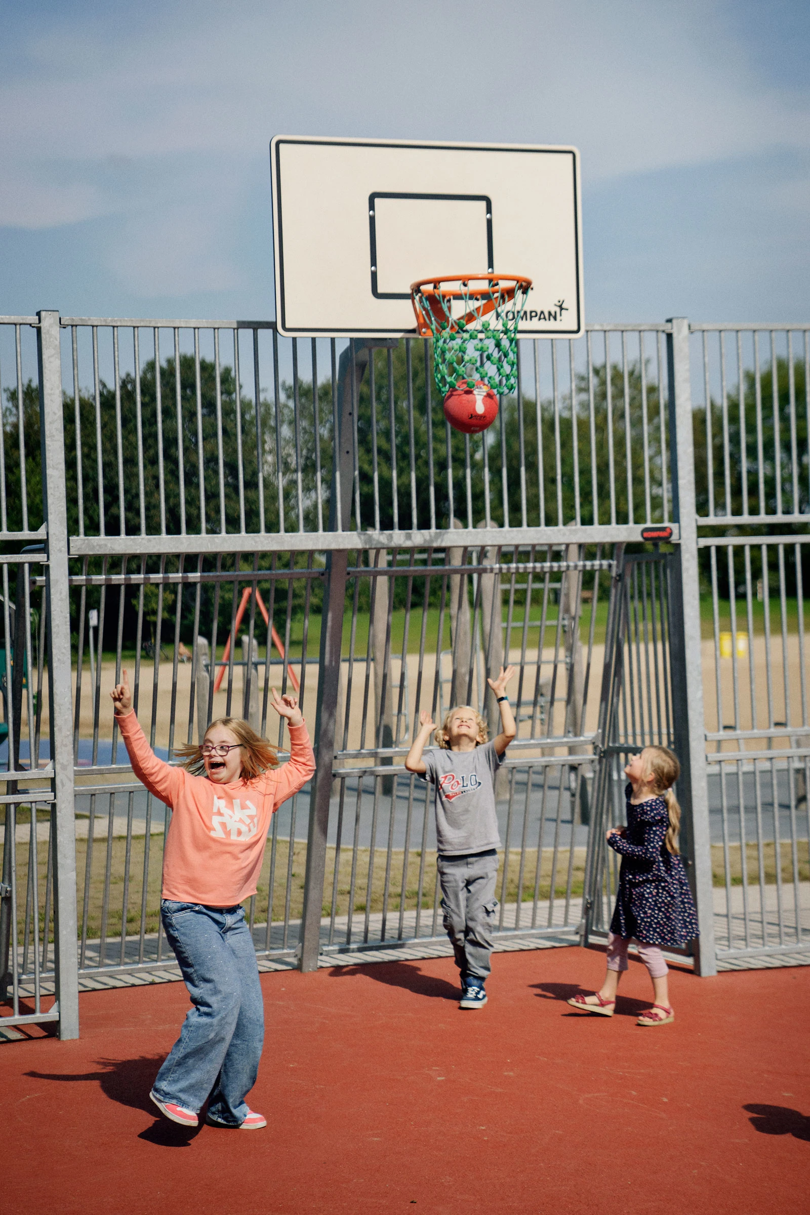 eine Betreuerin und ein Junge im Rollstuhl spielen auf einem Förderschule Spielplatz