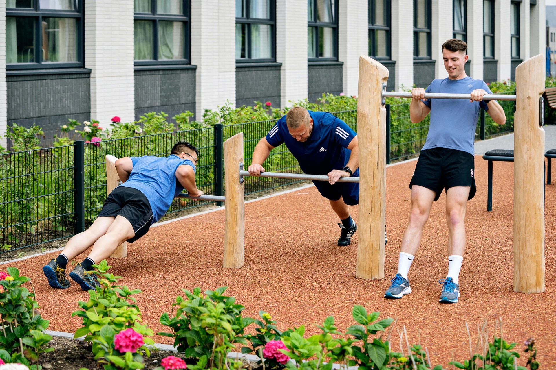 drie mannen doen push-ups op outdoor fitnessapparatuur in hout