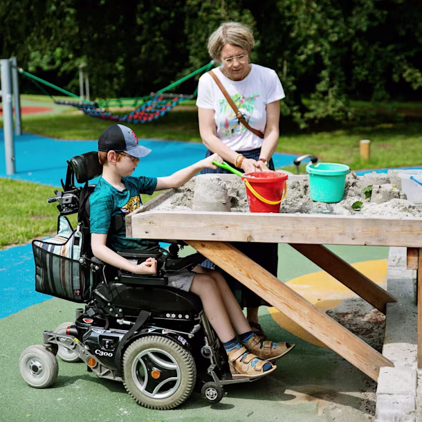 pojke i rullstol leker vid upphöjt sandbord