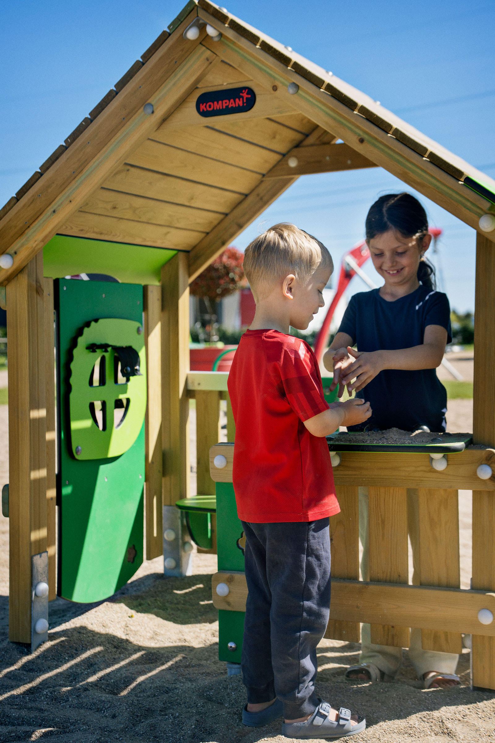 wooden playhouse on playground where children are playing. 