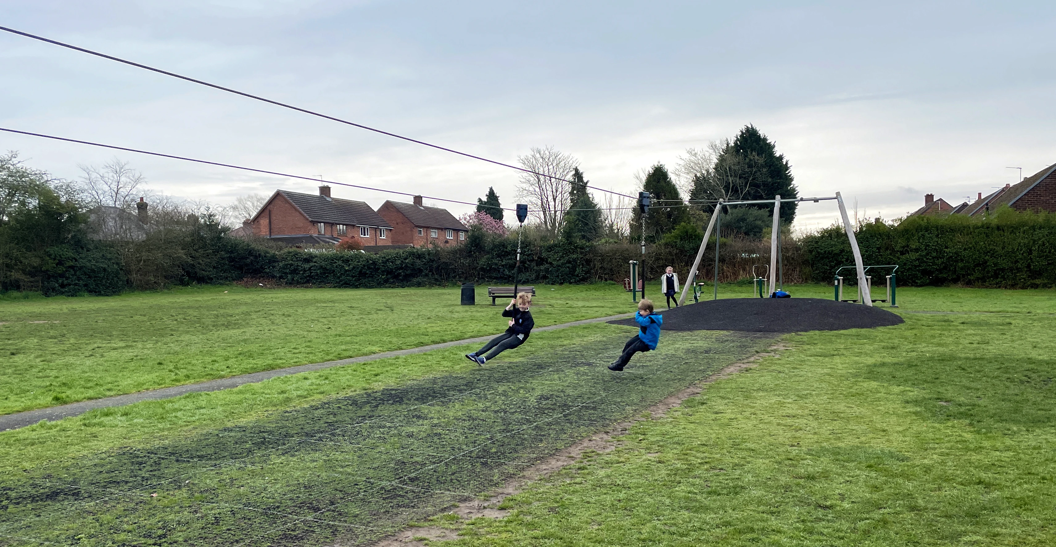 girl having fun on a playground zipline in a public park in England