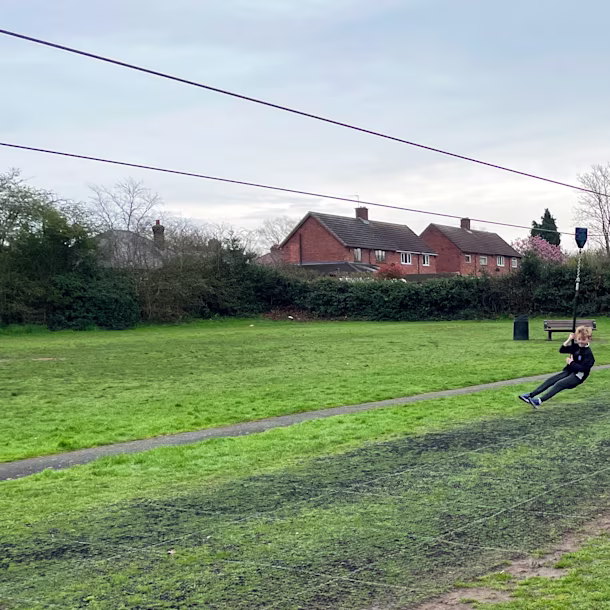 girl having fun on a playground zipline in a public park in England