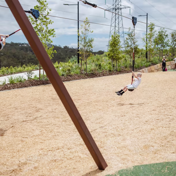 girl having fun on a playground zipline in a public park in England