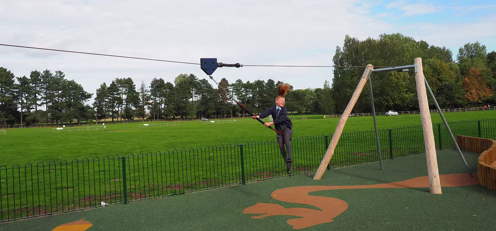 girl having fun on a playground zipline in a public park in England
