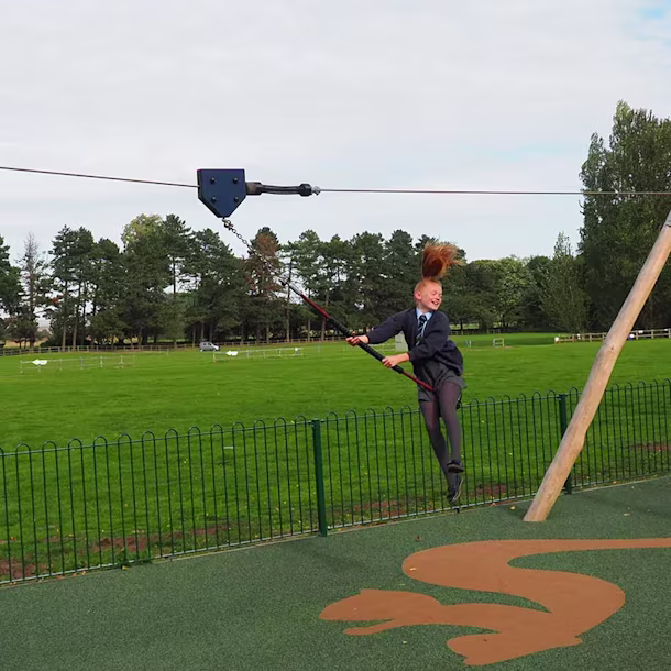 Mädchen hat Spaß auf einer Spielplatz Seilbahn in einem öffentlichen Park in England