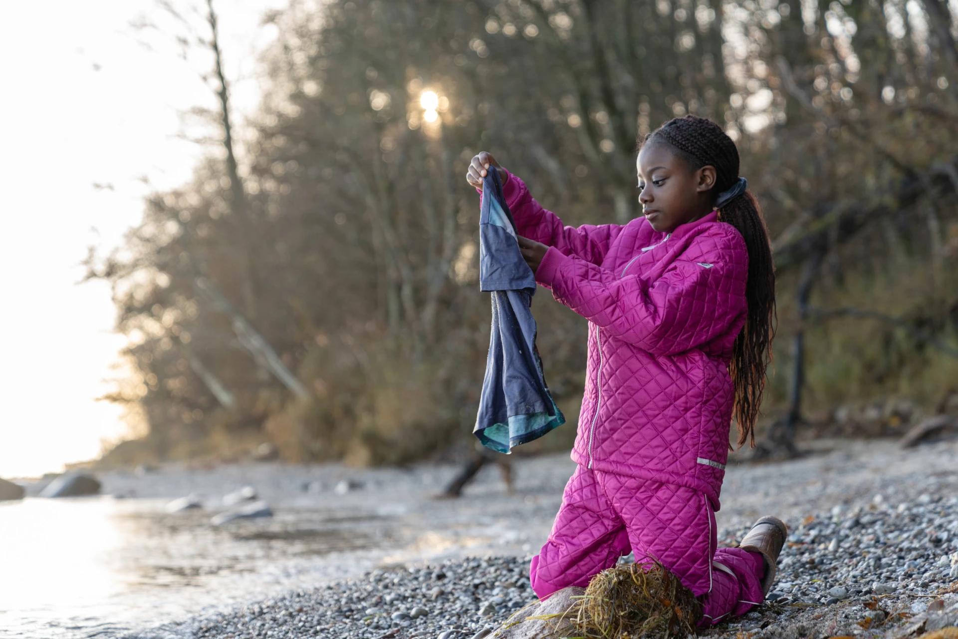 girl holding up old clothes found on a beach