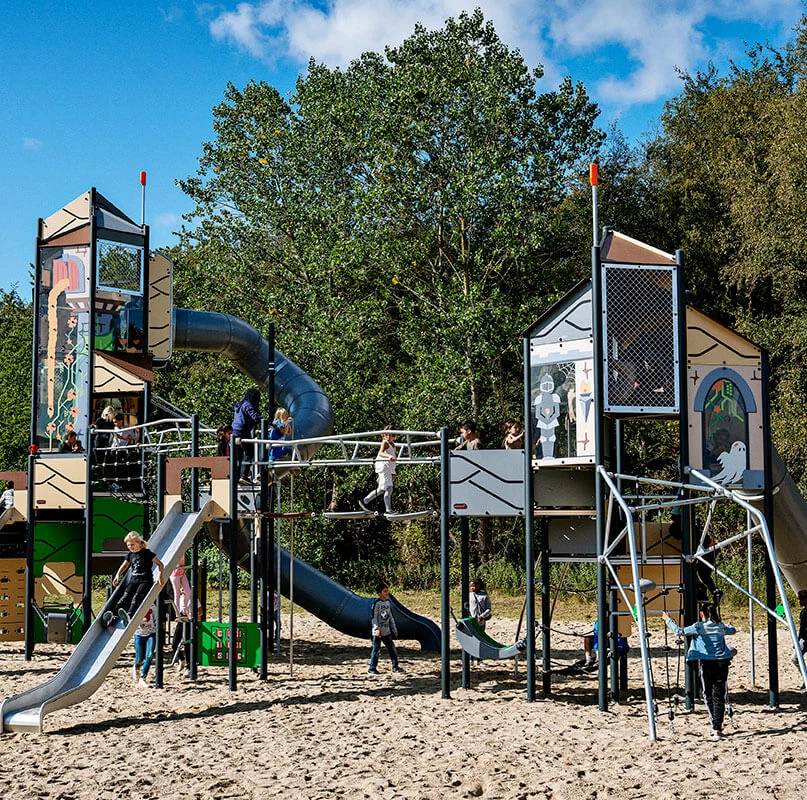Stort leksystem i en park med flera rutschkanor och klättermöjligheter
