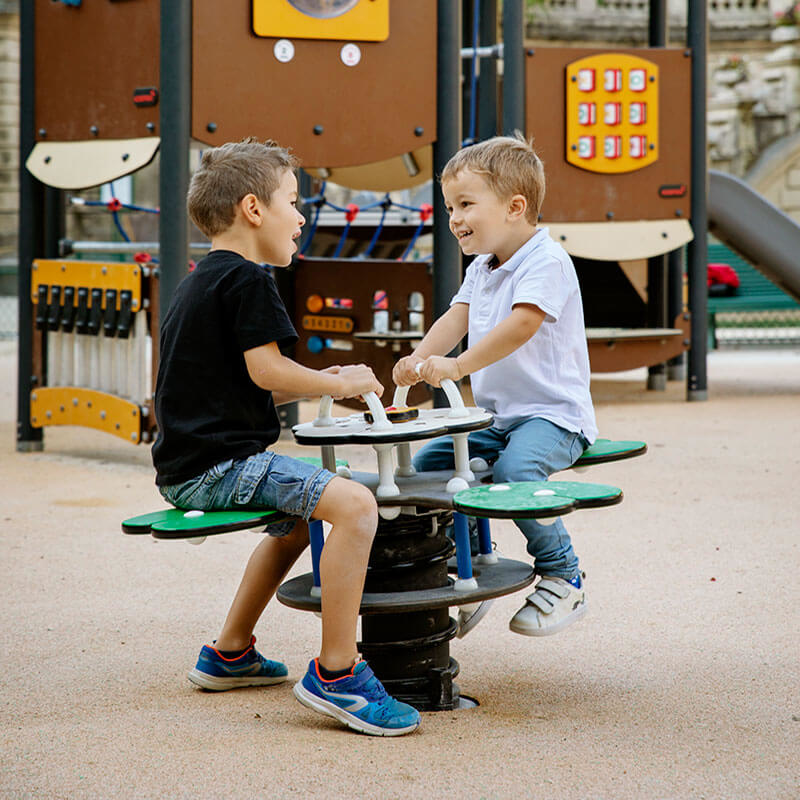 boys playing on a playground spring rider in a park