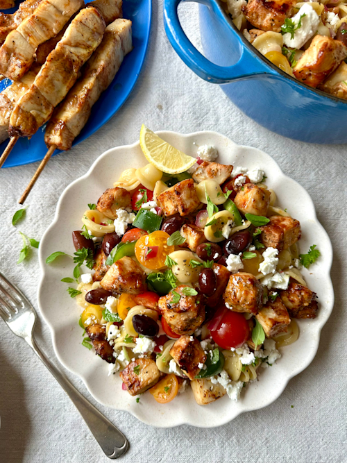 Greek salad penne in white plate on grey mat