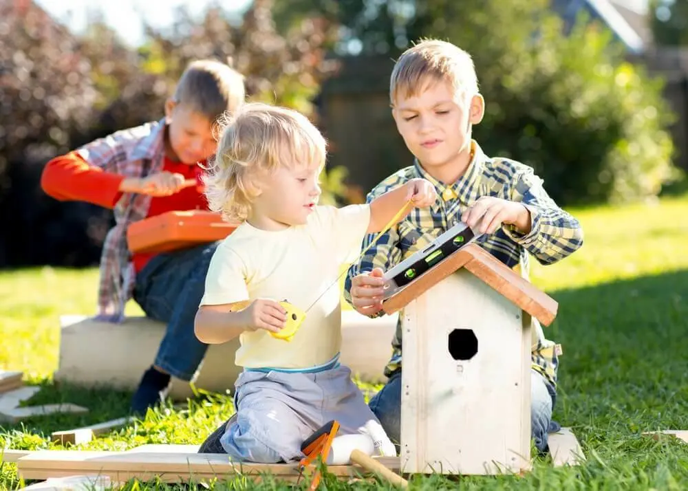 Drie kinderen in het gras met een houten tuinhuisje | Trois enfants dans l'herbe avec un kiosque en bois