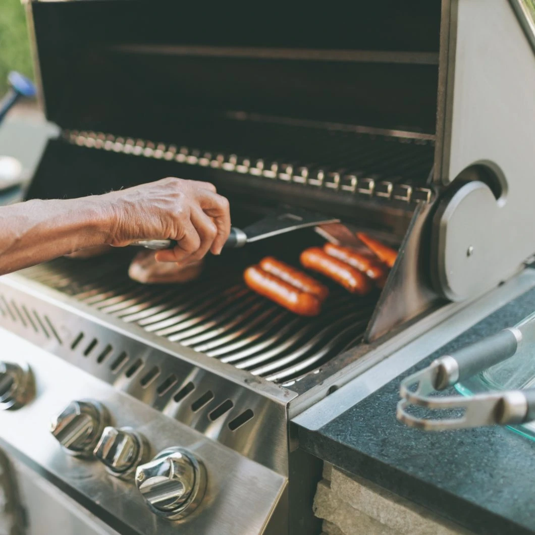 iemand die hotdogs grilt op een grill | personne qui fait griller des hot-dogs sur un gril