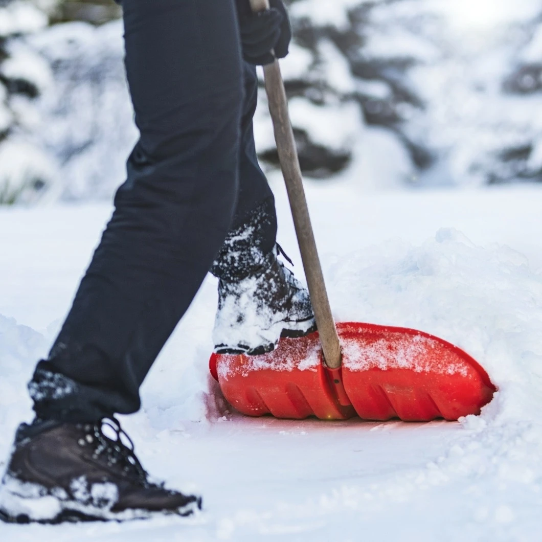 Een persoon schept sneeuw met een rode schep | Une personne déneige avec une pelle rouge 