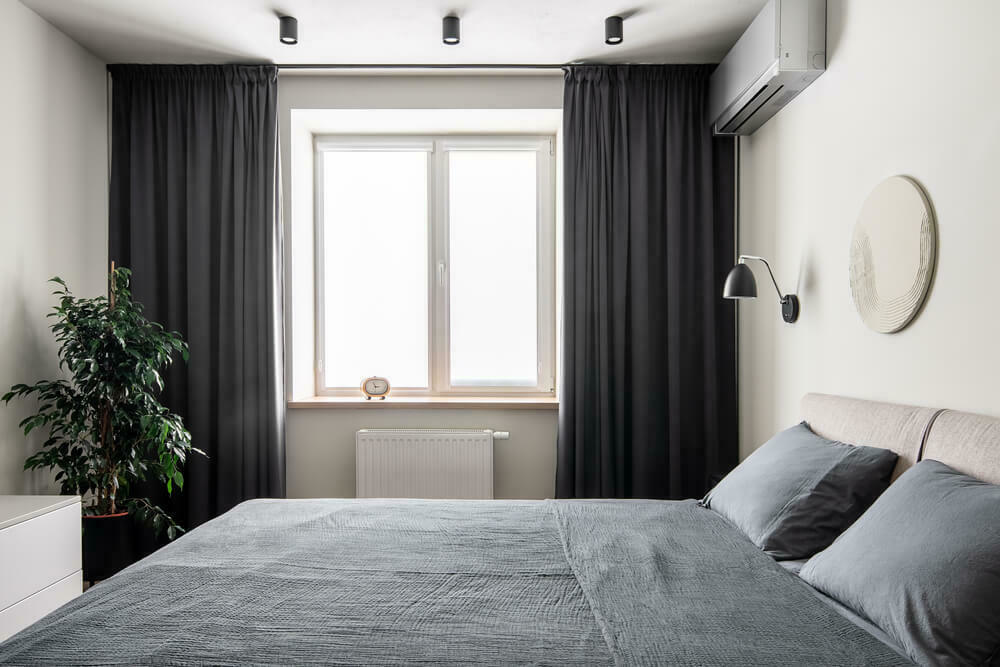 Een bed in een kamer voor het raam met gordijnen | Un lit dans une chambre devant la fenêtre avec des rideaux