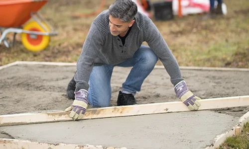 Man strijkt beton glad met gereedschap van Boels | Praxis