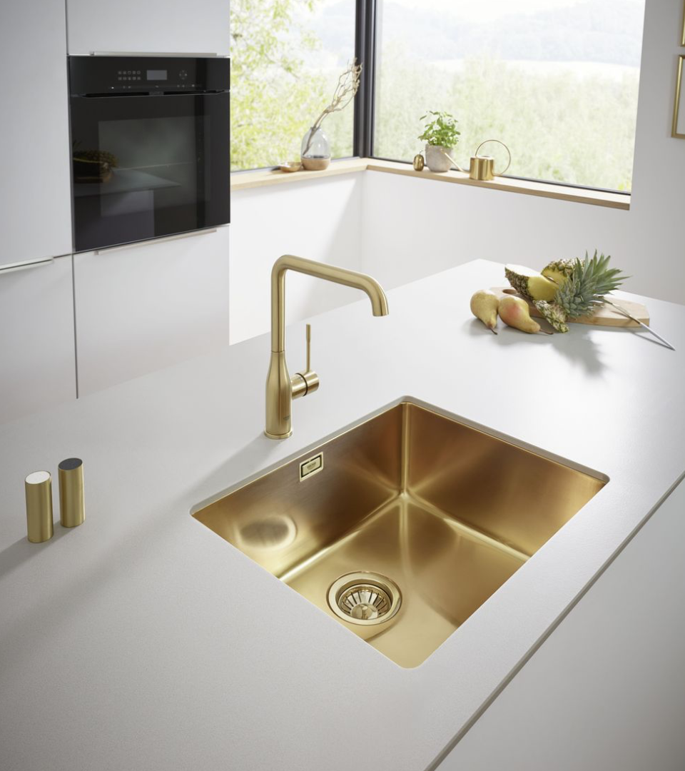 Gouden kraan en wasbak in een moderne witte keuken | Robinet et évier dorés dans une cuisine blanche moderne