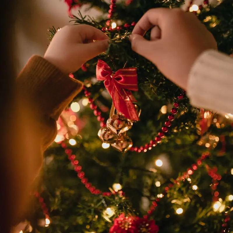 Kindje versiert de kerstboom | Un enfant décore le sapin de Noël