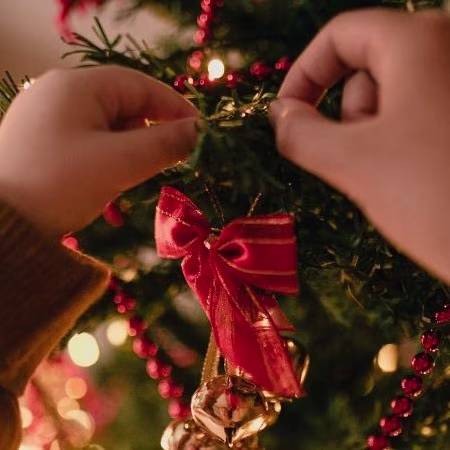 Kindje versiert de kerstboom | Un enfant décore le sapin de Noël