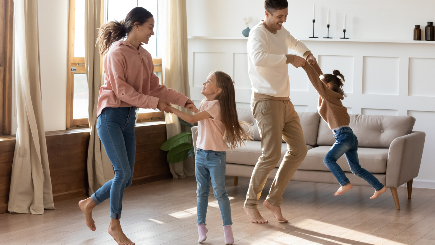 Een man, vrouw en een kind dansen op de vloer in de woonkamer | Un homme, une femme et un enfant dansent sur le sol du salon