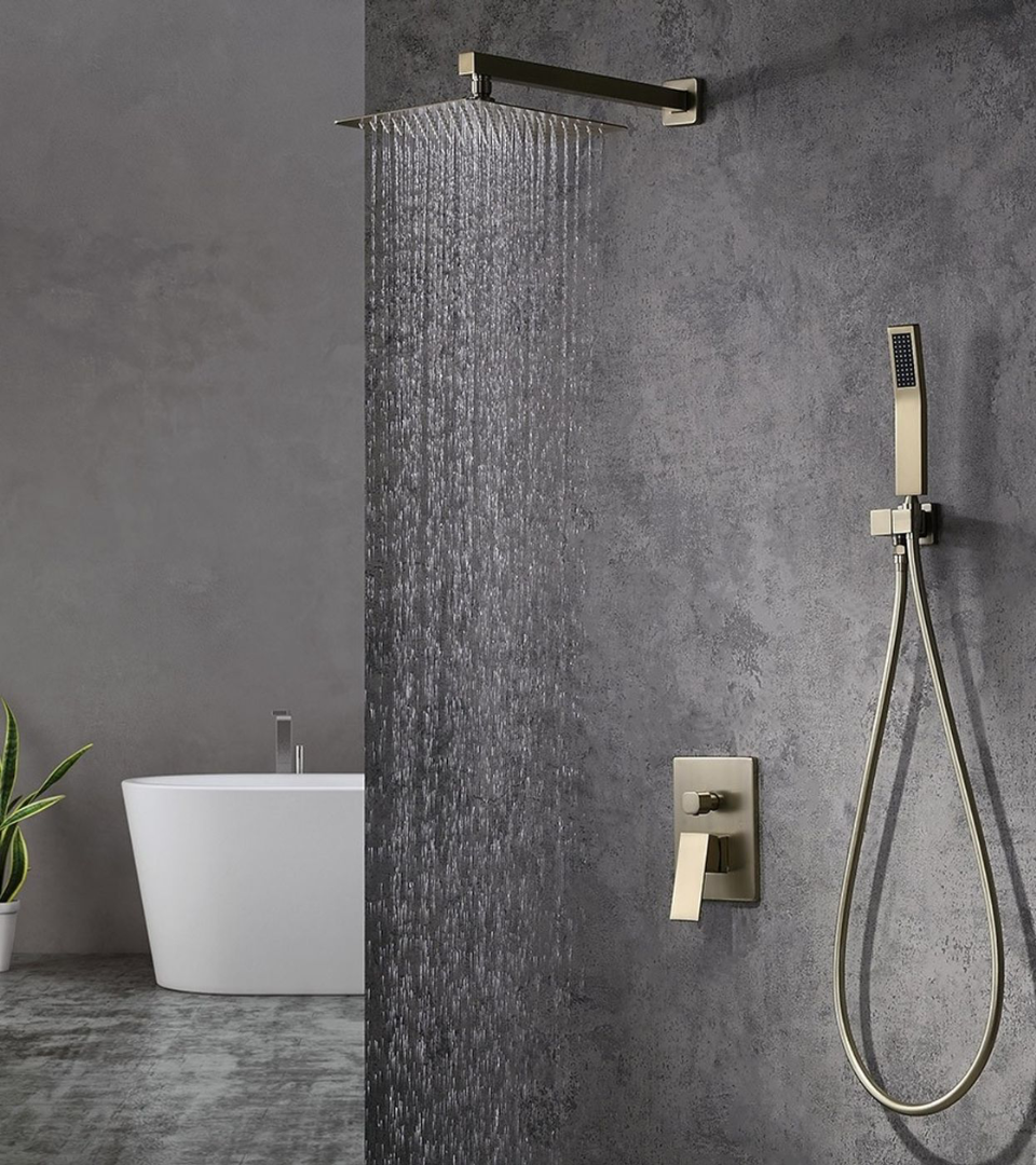 Een gouden douche in een donker grijze badkamer met een bad op de achtergrond | Douche dorée dans une salle de bains gris foncé avec une baignoire en arrière-plan