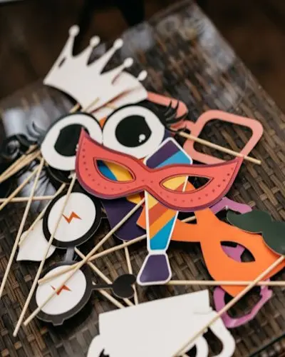 Fotobooth-accessoires op een tafel, met kleurrijke maskers, brillen en een kroon | Accessoires photobooth sur une table, avec masques colorés, lunettes et une couronne