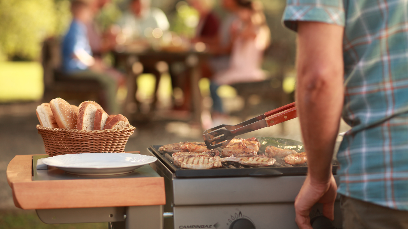 Man barbecued met vrienden aan tafel op de achtergrond | Homme faisant un barbecue avec des amis à une table à l'arrière-plan