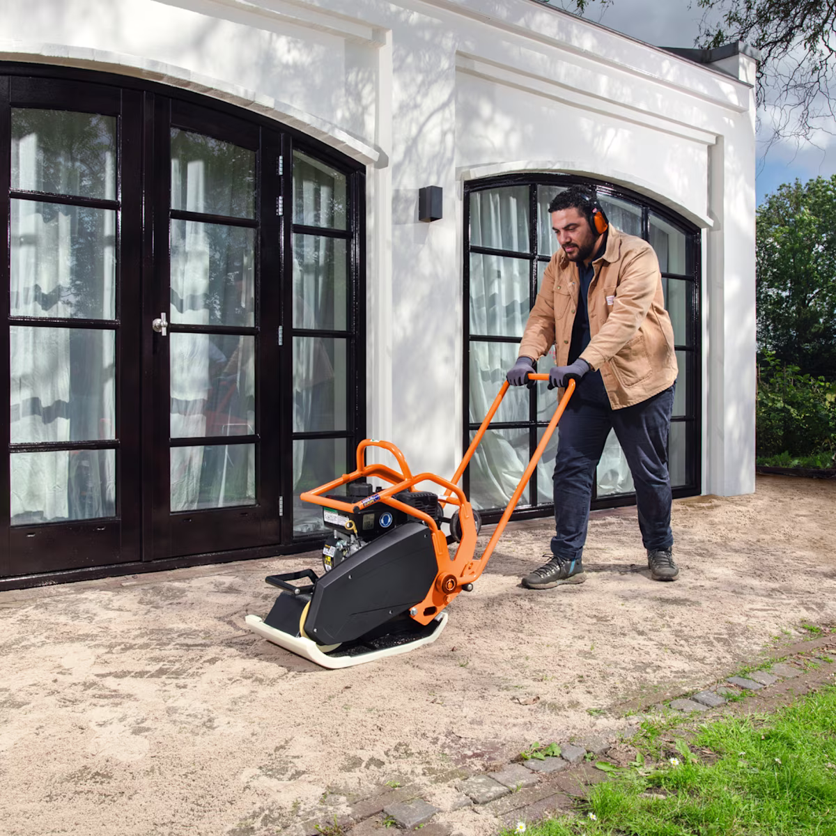 Een man trilt de grond aan met een trilplaat | Un homme compacte le sol avec une plaque vibrante