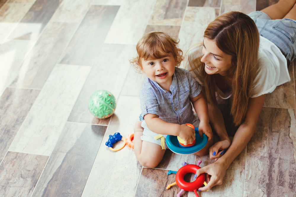 Een vrouw en een kind spelen op een vloer | Une femme et un enfant jouent sur un plancher