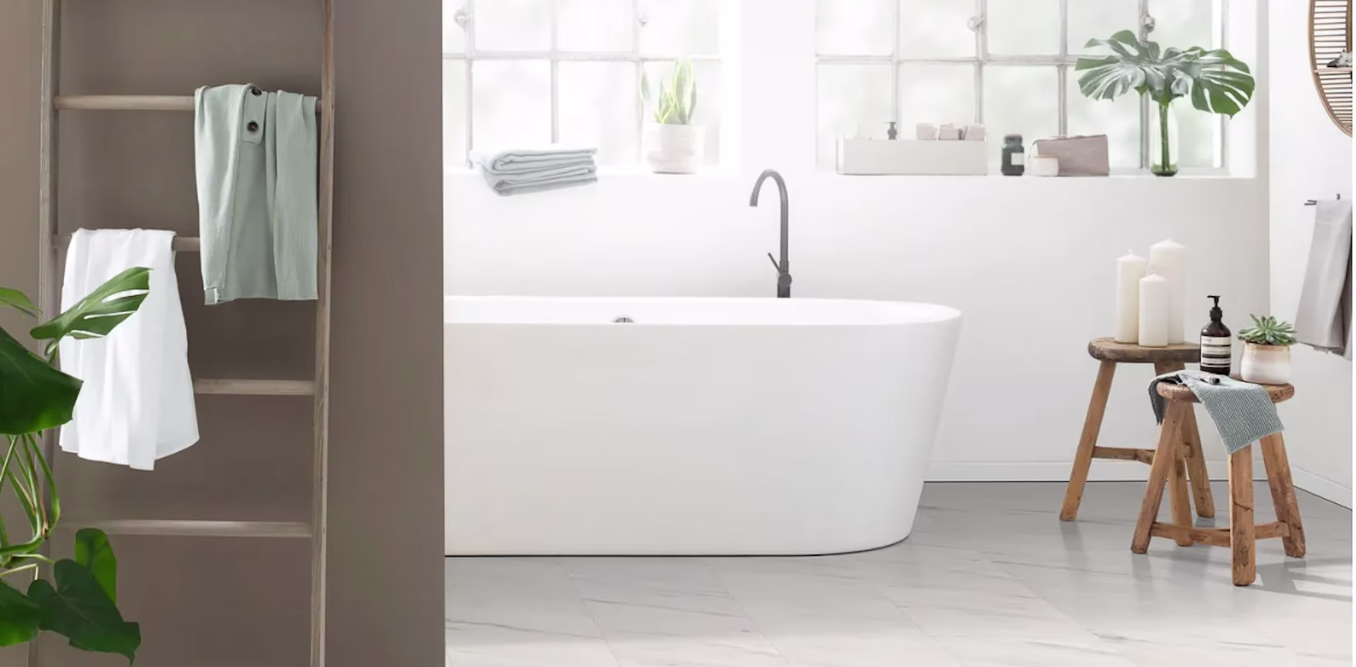 badkamer met wit bad, houten accesssoires en een badkamervloer van laminaat met marmer print