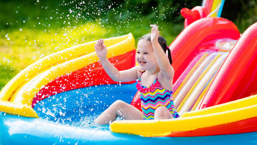 Een kindje speelt in een opblaas kinderzwembad met glijbaan | Un enfant joue dans une piscine gonflable avec toboggan