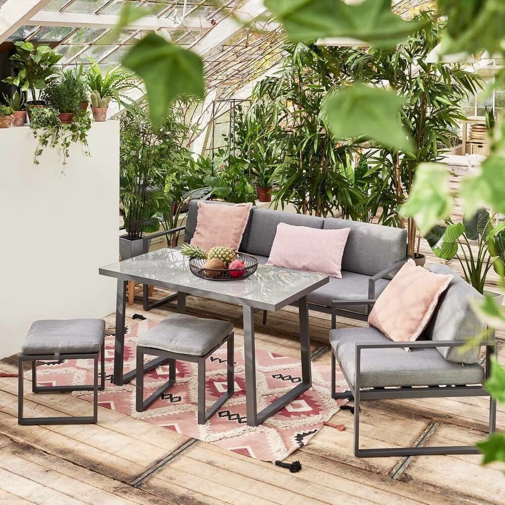 Een grijze loungeset op een houten vloer onder een overkapping | Un salon gris posé sur un plancher en bois sous un auvent