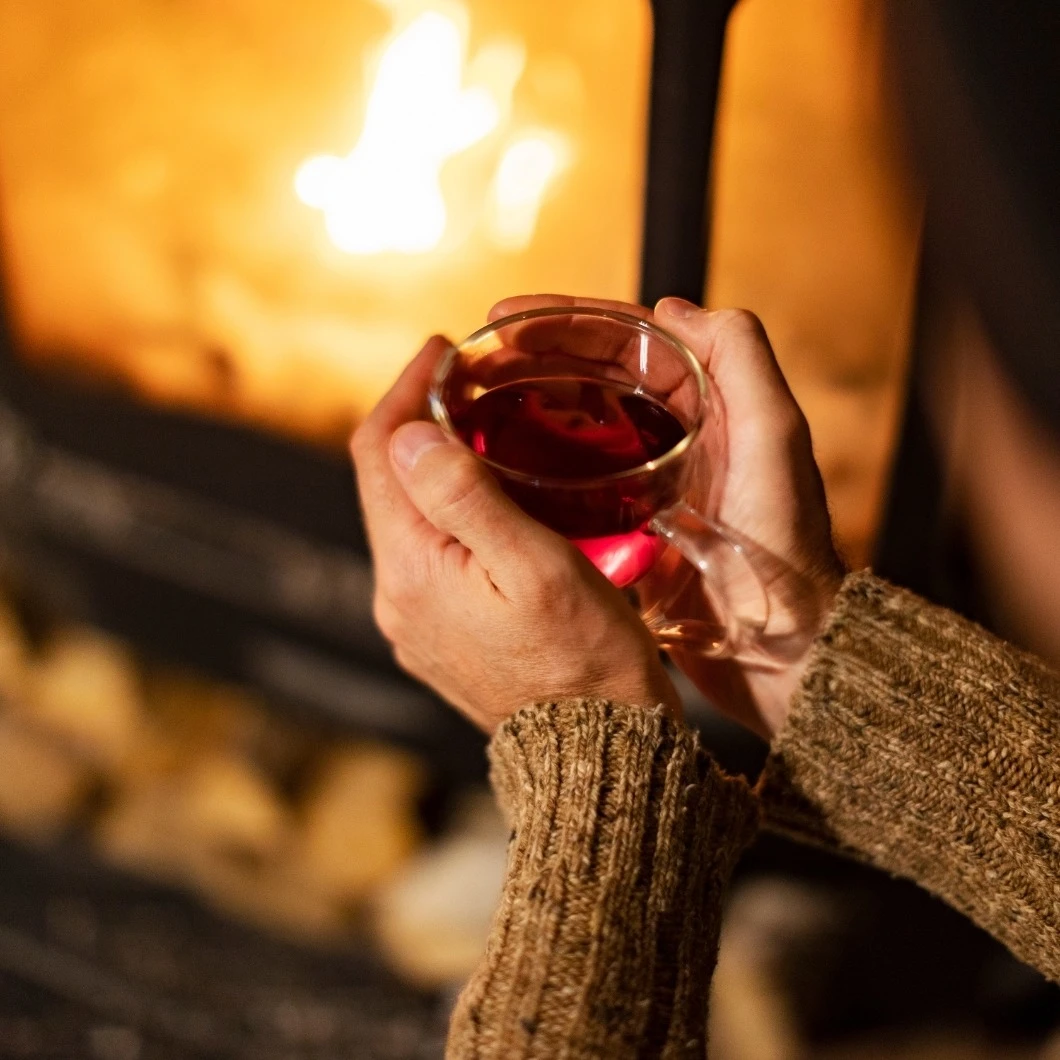 Een persoon met een glas thee voor een open haard | Une personne avec un verre de thé devant une cheminée