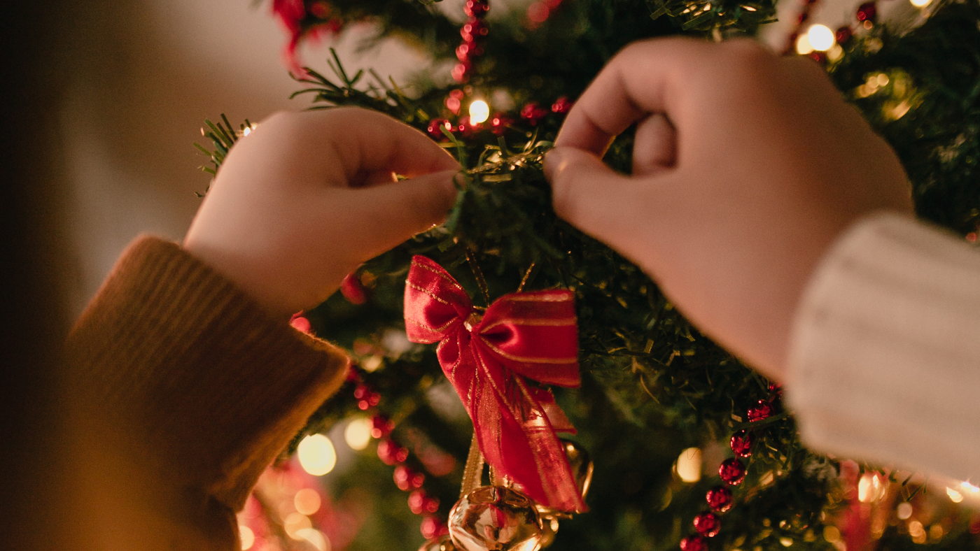 Kindje versiert de kerstboom | Un enfant décore le sapin de Noël