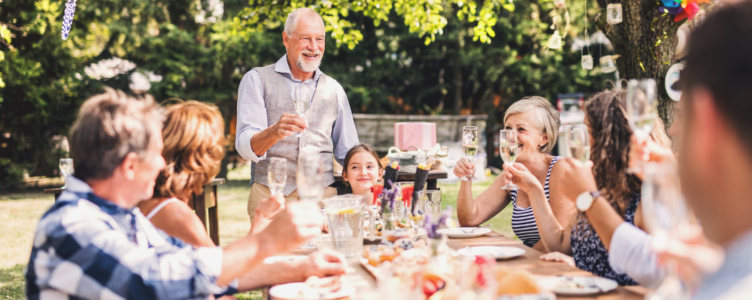 Een grote familie rond een tafel op een tuinfeestje | Une grande famille autour d'une table lors d'une garden party