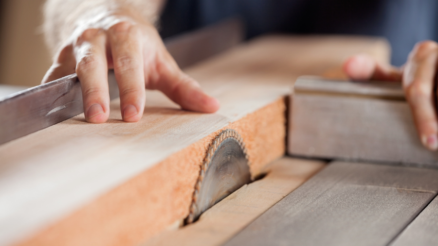 Iemand bewerkt een stuk hout met een zaag | Une personne travaille sur une pièce de bois à l'aide d'une scie